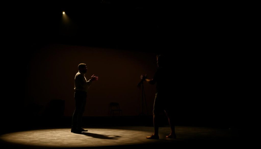A dimly lit theater stage, the spotlight shining on two actors engaged in a captivating bilingual performance. In the foreground, their expressive gestures and nuanced body language convey the emotional depth of the scene, while the background features a minimalist set design that blends elements of Spanish and international influences. The lighting casts dramatic shadows, creating an atmospheric and contemplative mood that invites the audience to immerse themselves in the multicultural narrative unfolding before them. The camera angle is slightly elevated, offering a perspective that captures the dynamic interplay between the performers and the stage, showcasing the athletic poetics and bilingual engagement that define this captivating theatrical experience. A dimly lit theater stage, the spotlight shining on two actors engaged in a captivating bilingual performance. In the foreground, their expressive gestures and nuanced body language convey the emotional depth of the scene, while the background features a minimalist set design that blends elements of Spanish and international influences. The lighting casts dramatic shadows, creating an atmospheric and contemplative mood that invites the audience to immerse themselves in the multicultural narrative unfolding before them. The camera angle is slightly elevated, offering a perspective that captures the dynamic interplay between the performers and the stage, showcasing the athletic poetics and bilingual engagement that define this captivating theatrical experience.